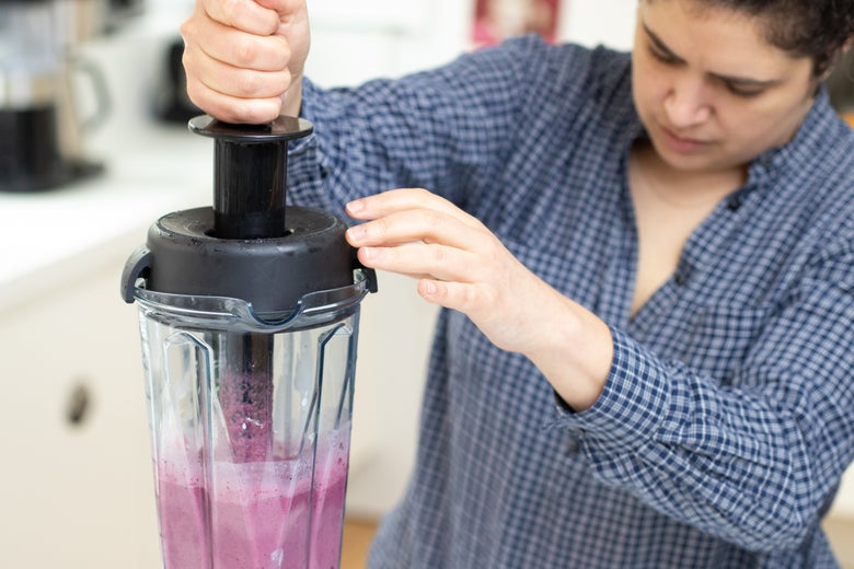 Woman using the blender's tamper.